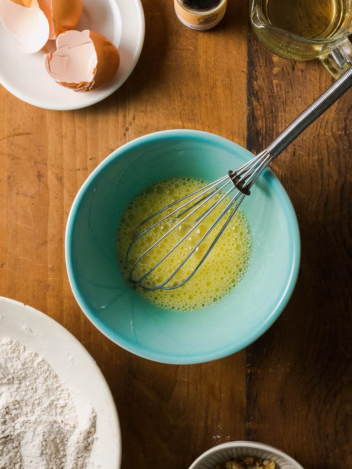 Eggs whisked to frothy bubbles in a small blue bowl.