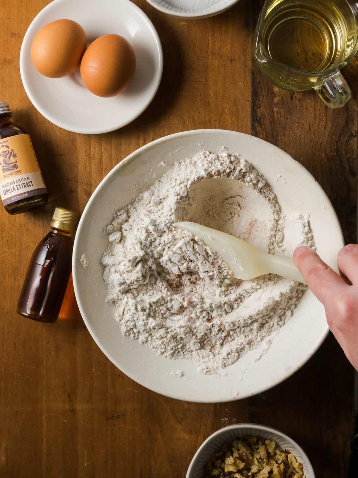 Gluten free flour and oat flour being stirred in a white bowl.