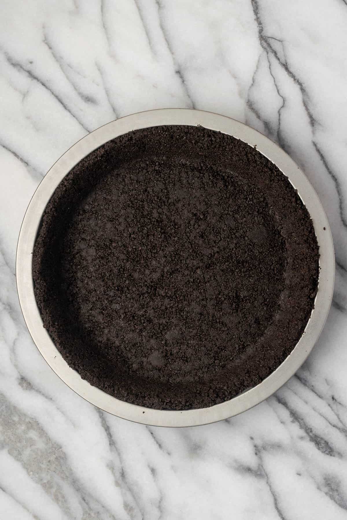 A gluten free Oreo pie crust sitting on a marble counter.