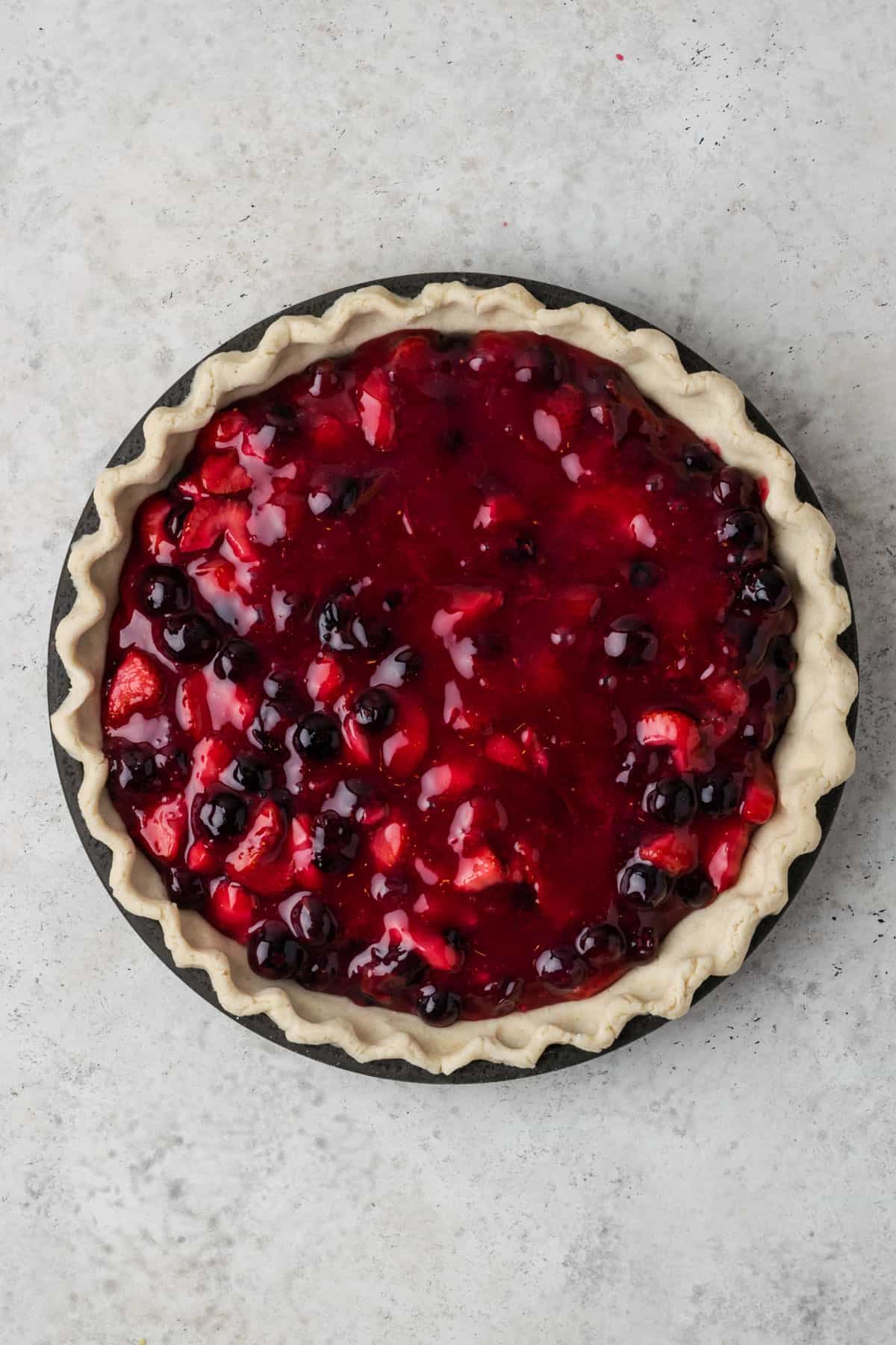 Strawberry blueberry pie filling poured into an unbaked pie shell.