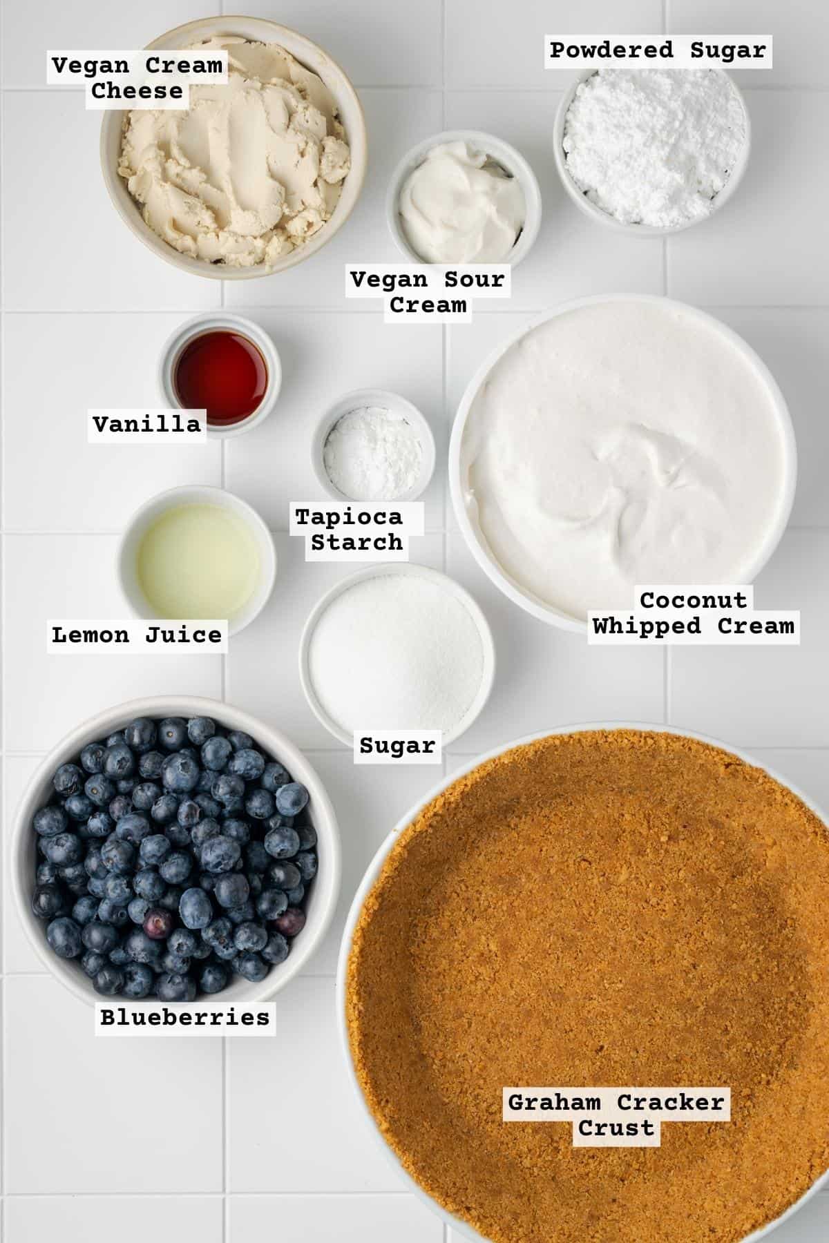 Ingredients for no bake blueberry cheesecake on a white tile table.