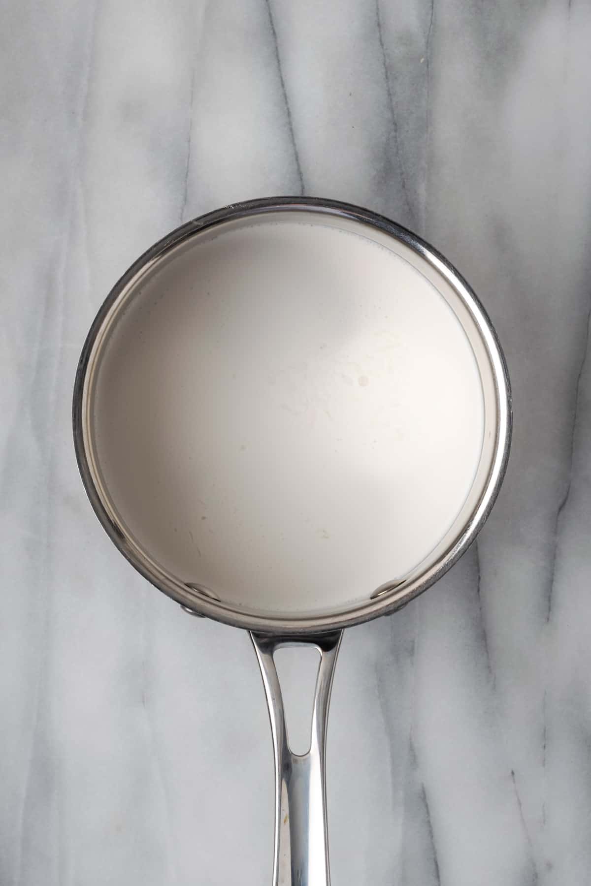 A small saucepan being used to heat heavy cream.