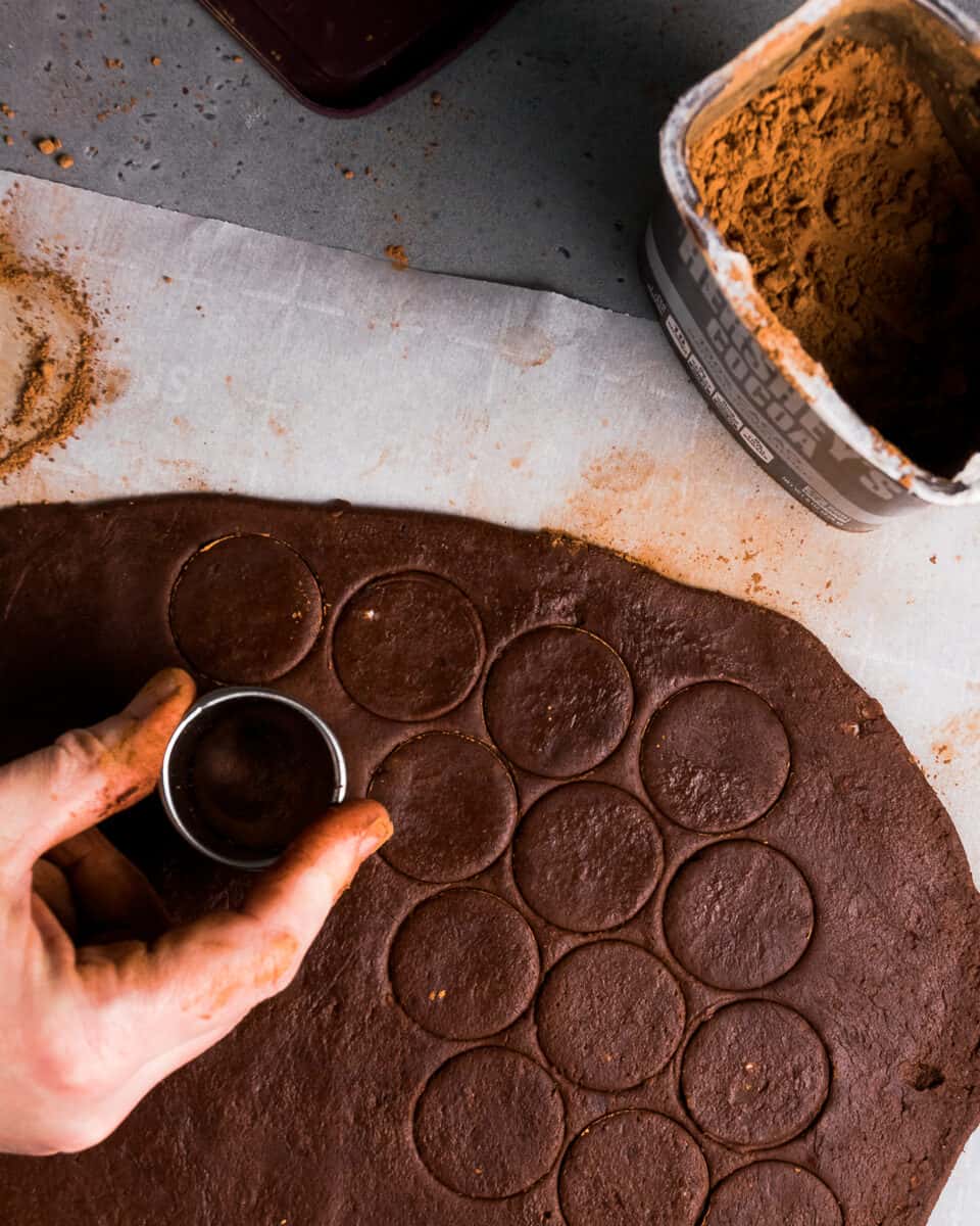 A small circle cookie cutter cutting out thin mint cookies from a sheet of cookie dough.