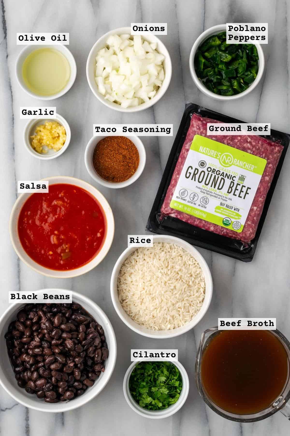 Ingredients for mexican beef and rice skillet on a white marble table.