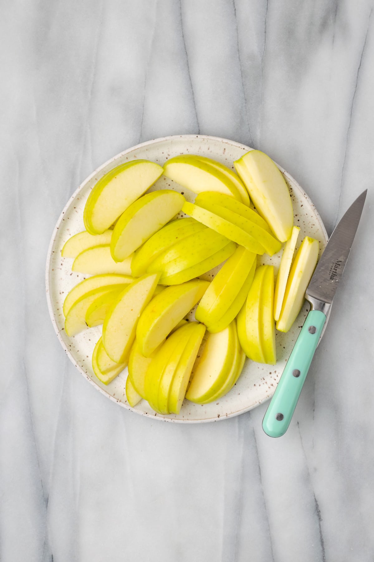 Sliced apples on a white ceramic plate.