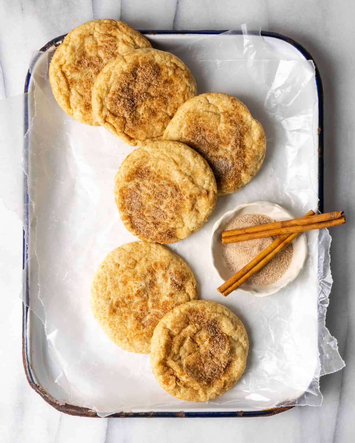 Cinnamon sugar cookies laying on a white baking tray. 