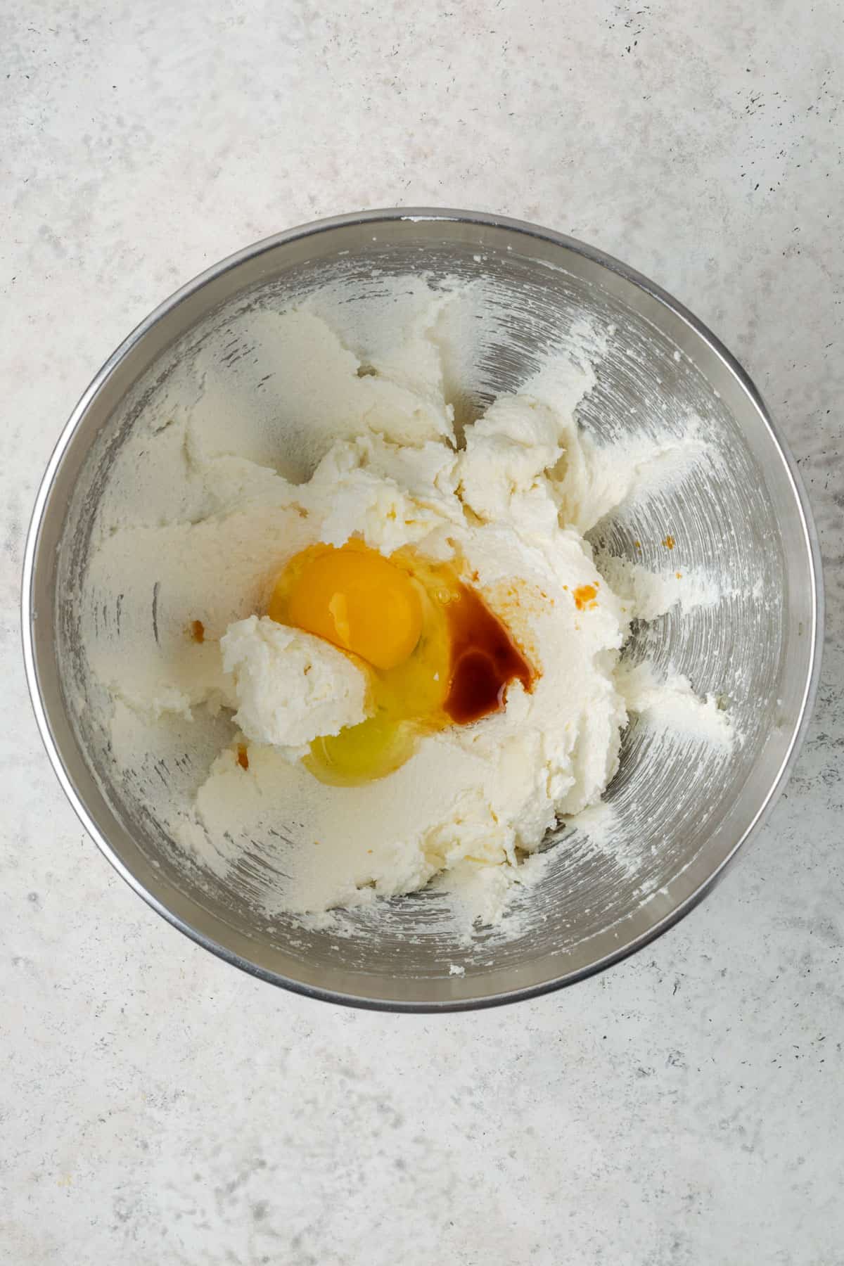 Egg and vanilla added to the creamed butter and sugar in a metal mixing bowl. 