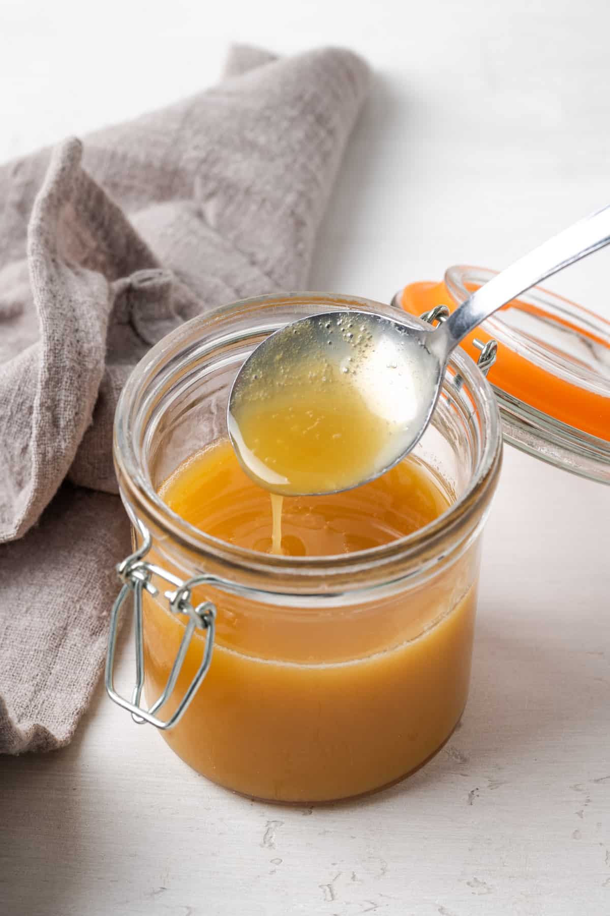 Dairy free sweetened condensed milk dripping from a spoon into a glass jar.