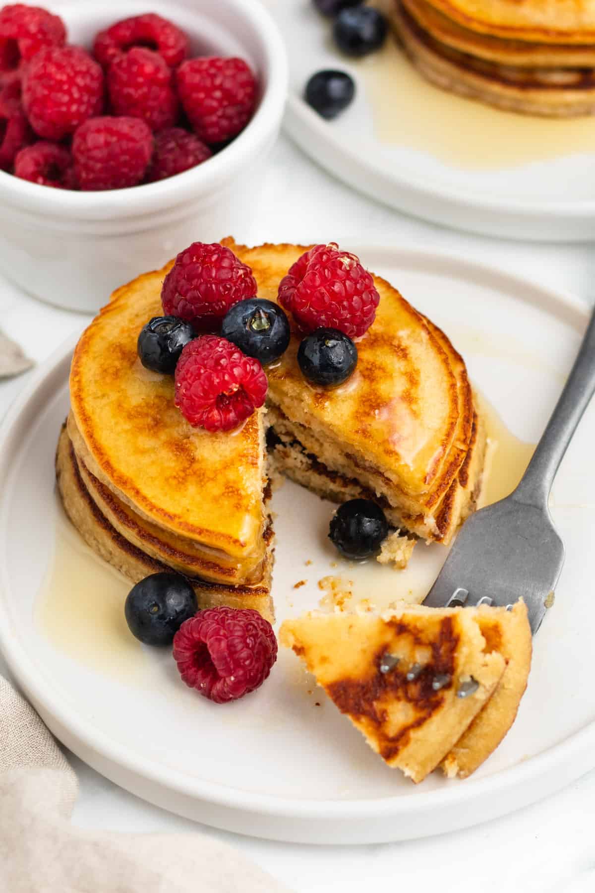 A stack of grain free pancakes with a bite being taken out. 