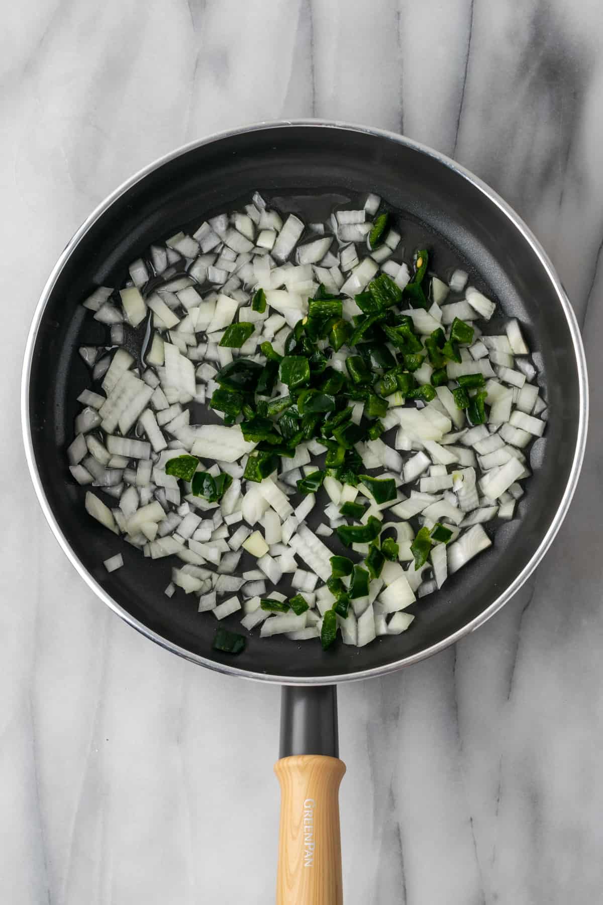 Diced onions and poblano peppers cooking in a nonstick skillet.
