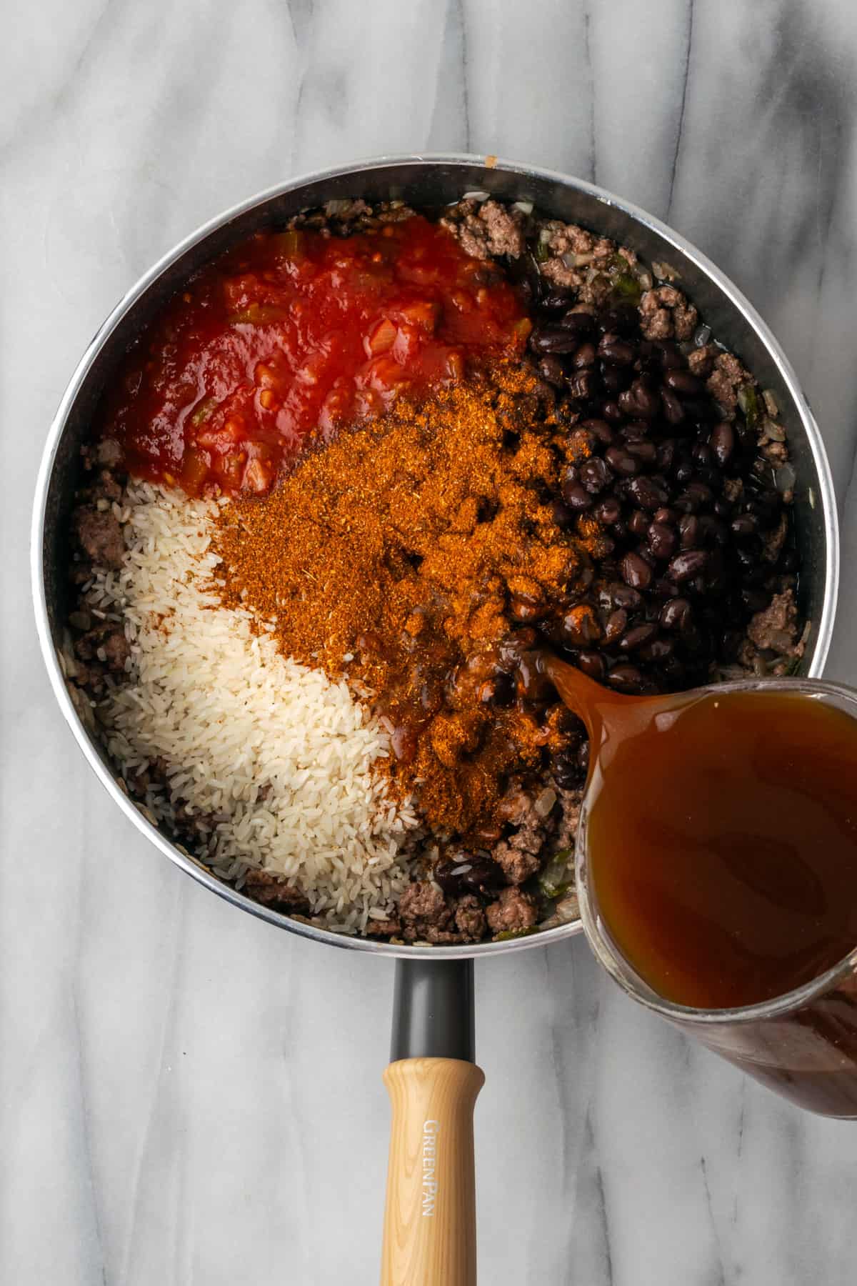 Rice, salsa, beans, taco seasoning and beef broth added to the skillet with the cooked ground beef.