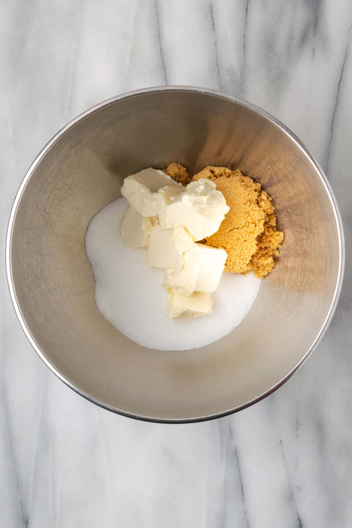 Sugar, brown sugar and butter combined together in the bowl of an electric mixer.