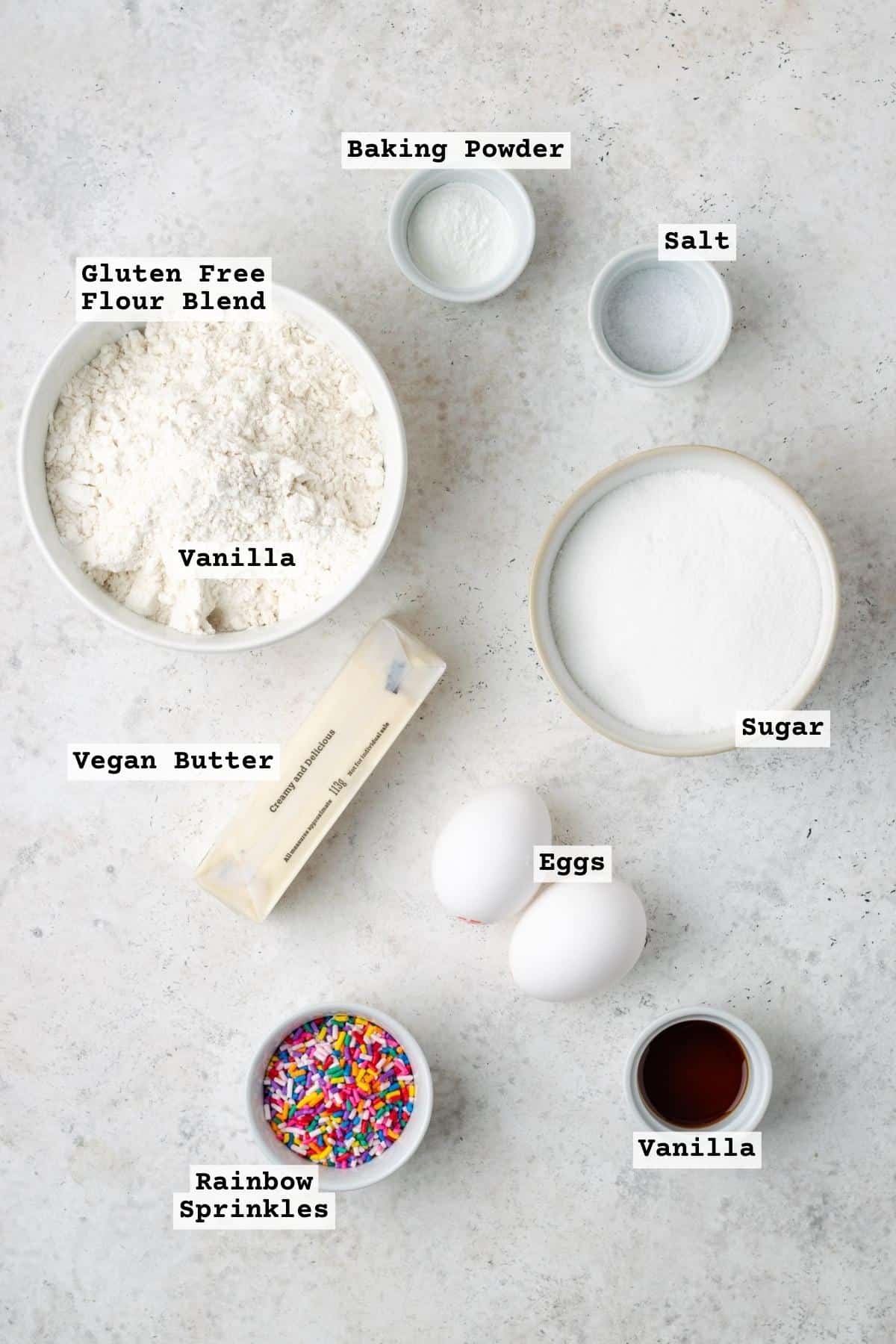 Ingredients for sprinkle sugar cookies on a white table. 