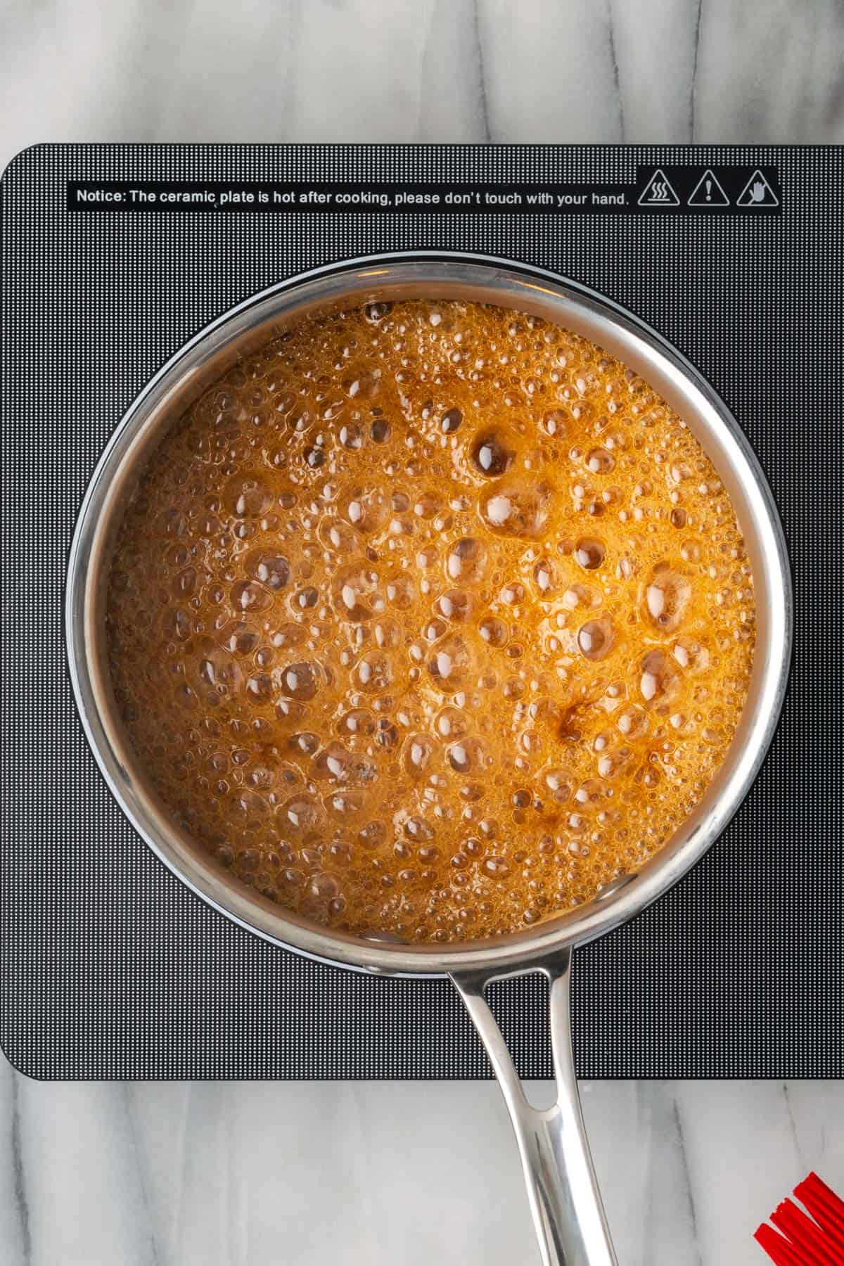 Sugar bubbling in a metal saucepan.