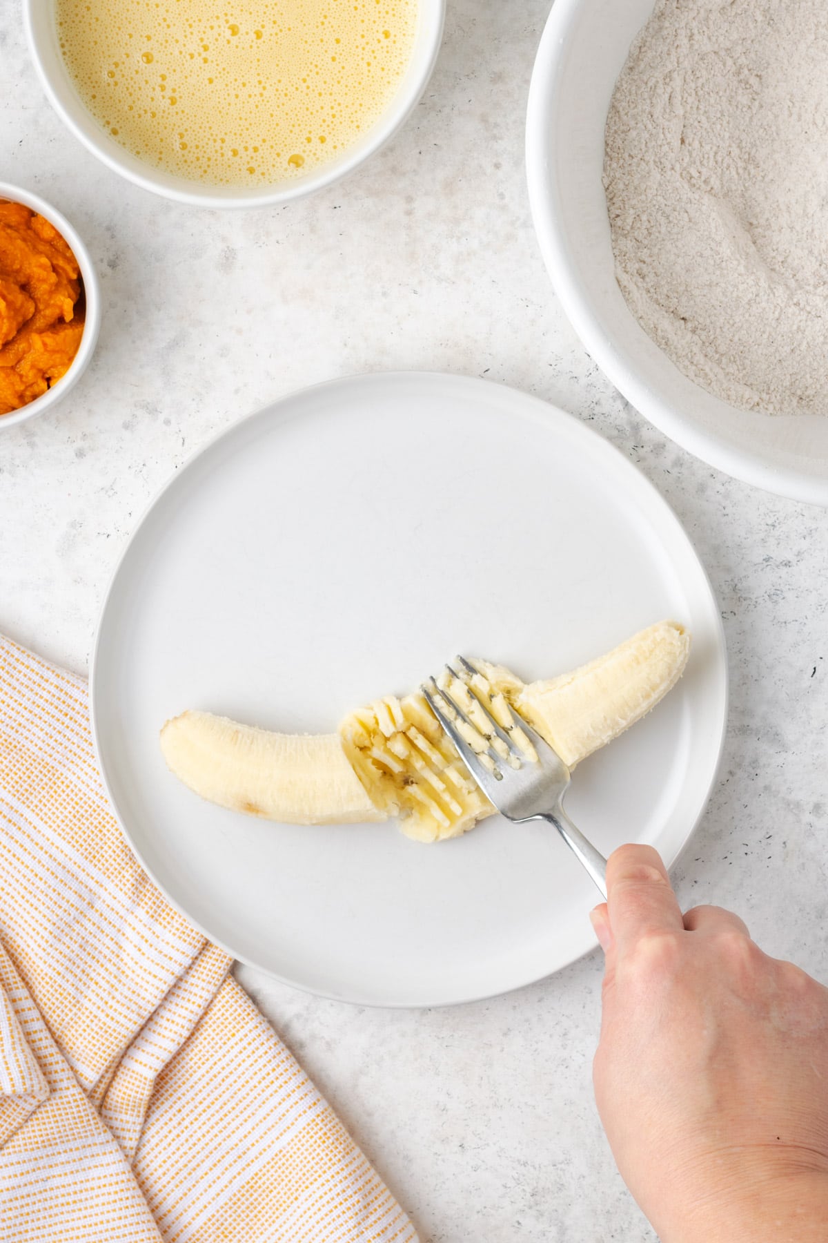 A single banana being mashed with a fork. 