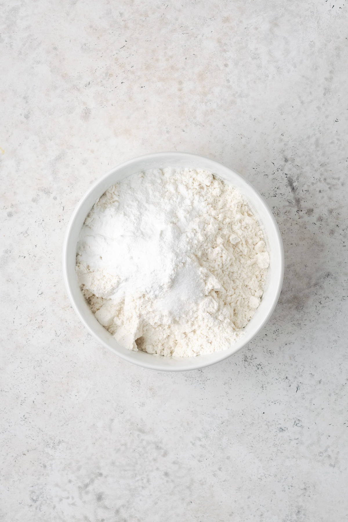 Gluten free flour, baking powder and salt combined in a small white bowl. 