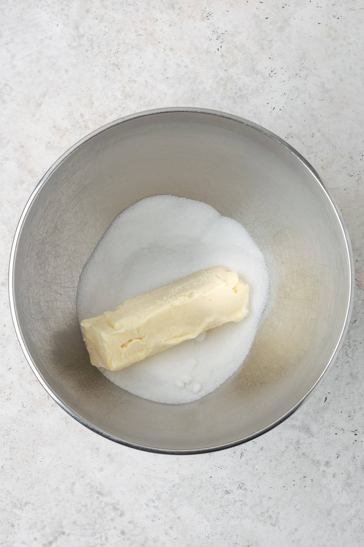 Sugar and butter combined in a large metal mixing bowl.