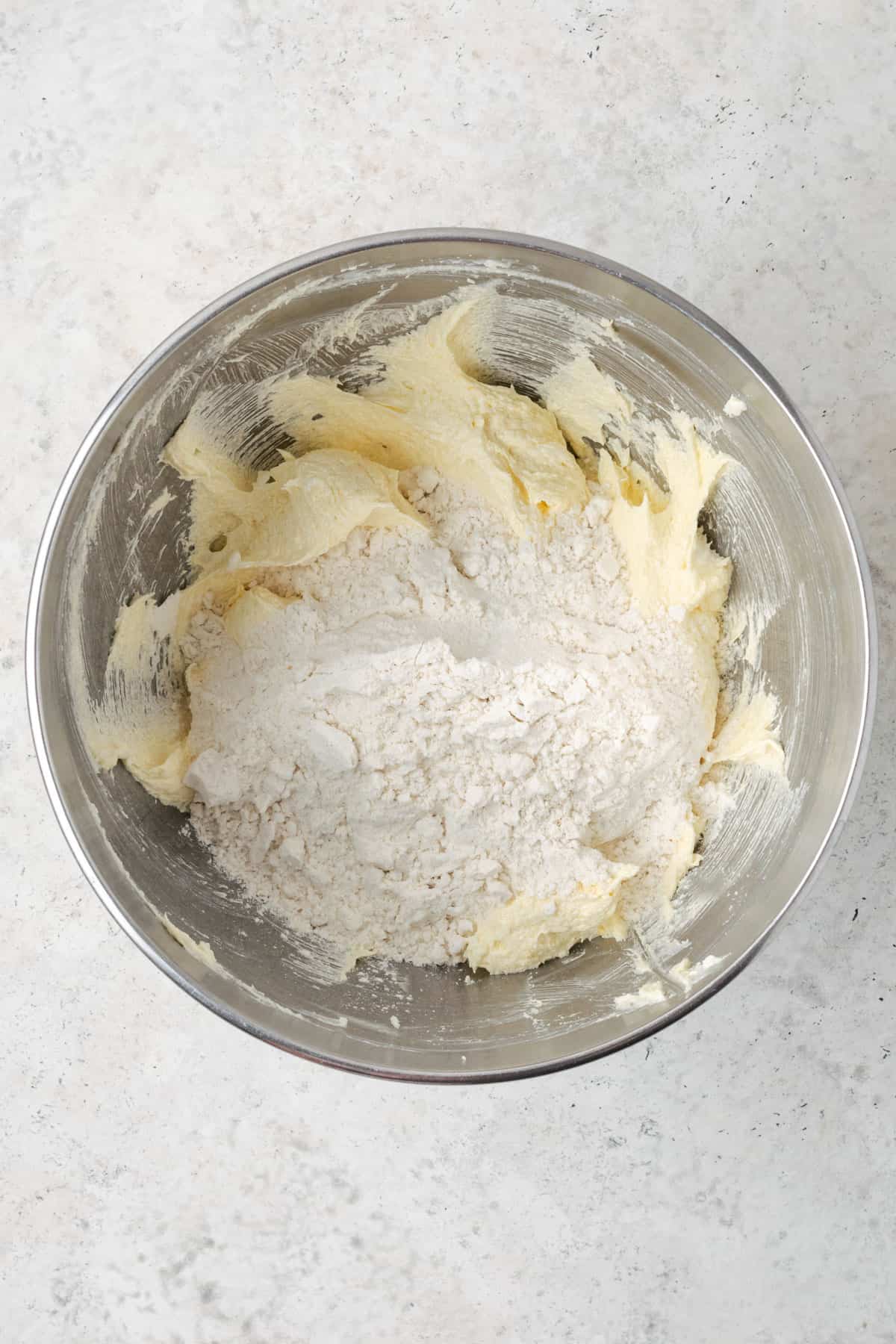 Dry ingredients being added to the mixing bowl with the creamed butter and sugar.