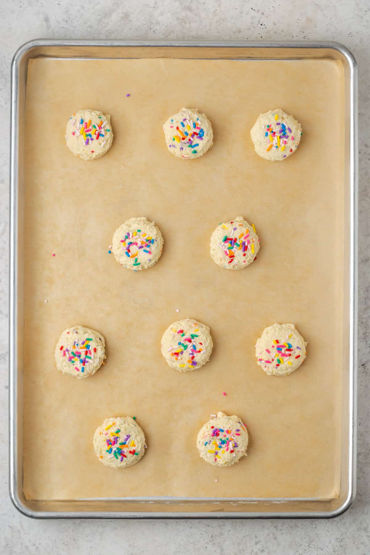 Unbaked sugar cookie dough balls on a baking sheet. 