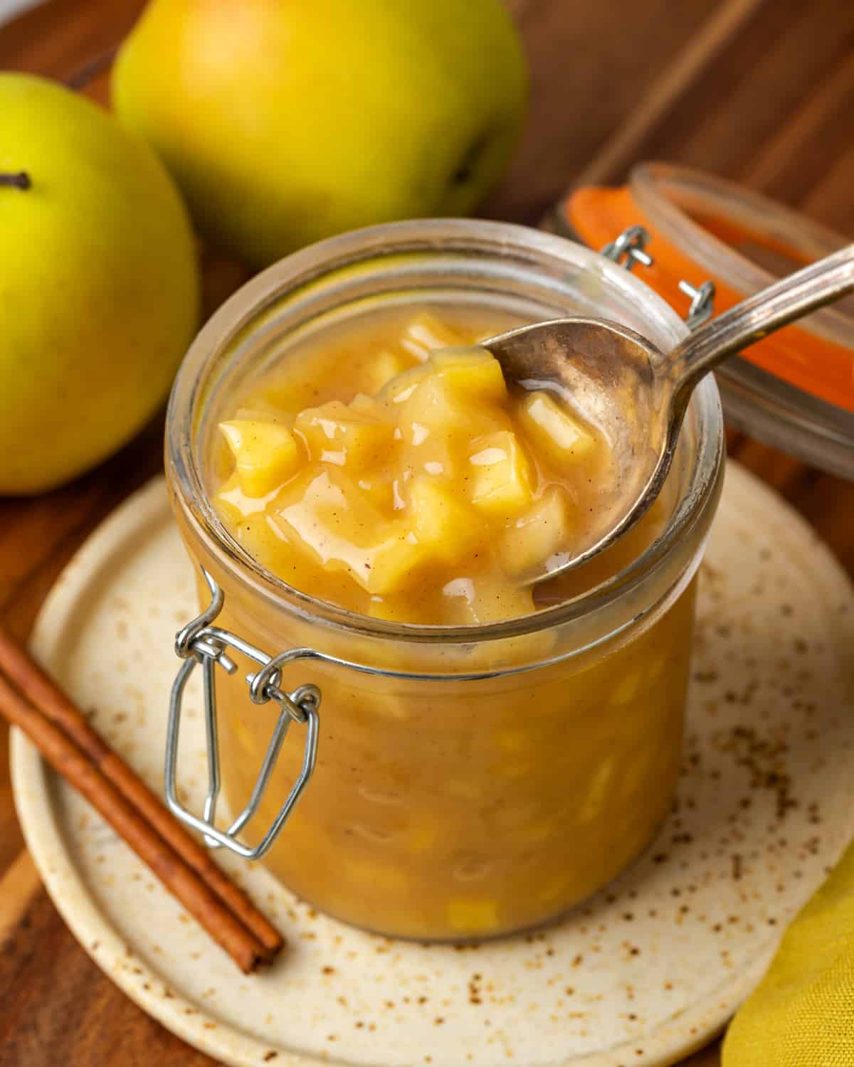 A spoon scooping homemade apple pie filling from a glass jar.