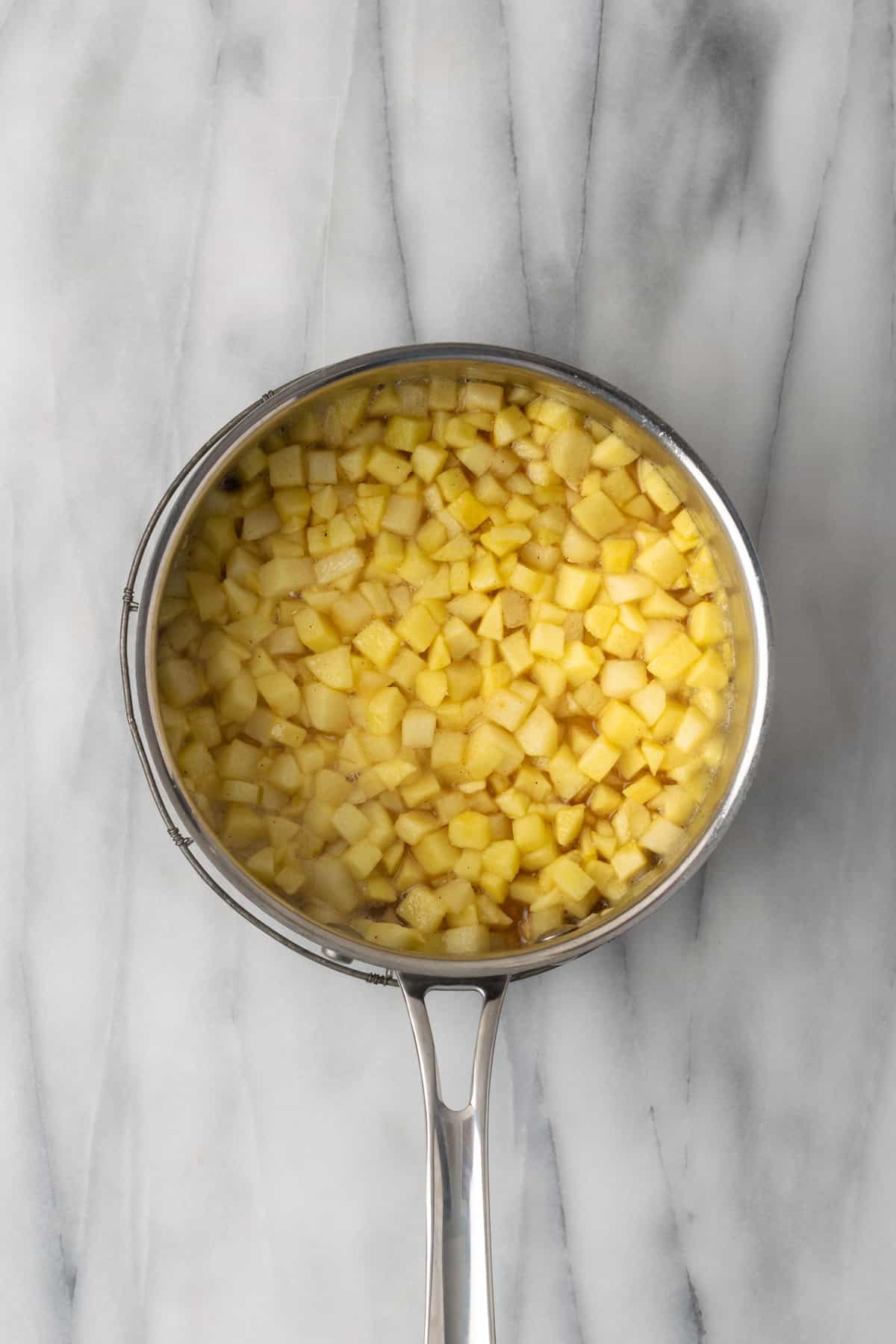 Cooked apple mixture in a metal saucepan.