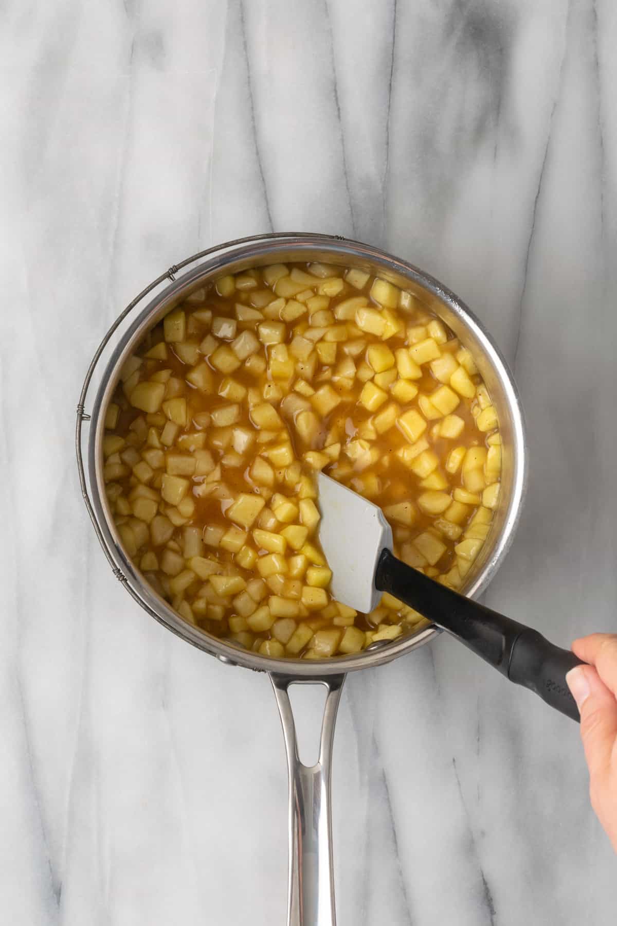 Cooked apple pie filling being stirred with a spatula.