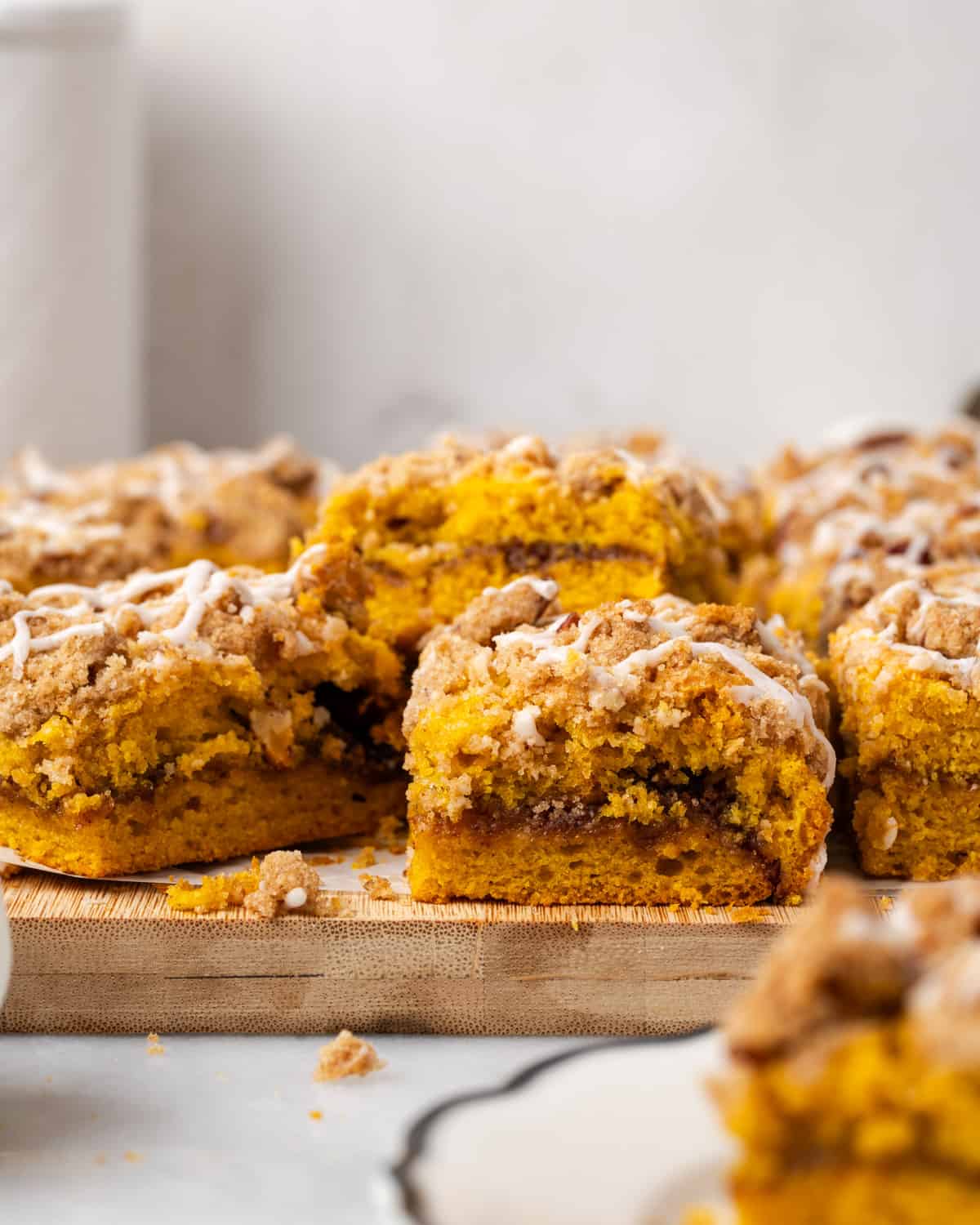 Squares of pumpkin coffee cake scattered on a wood cutting board.