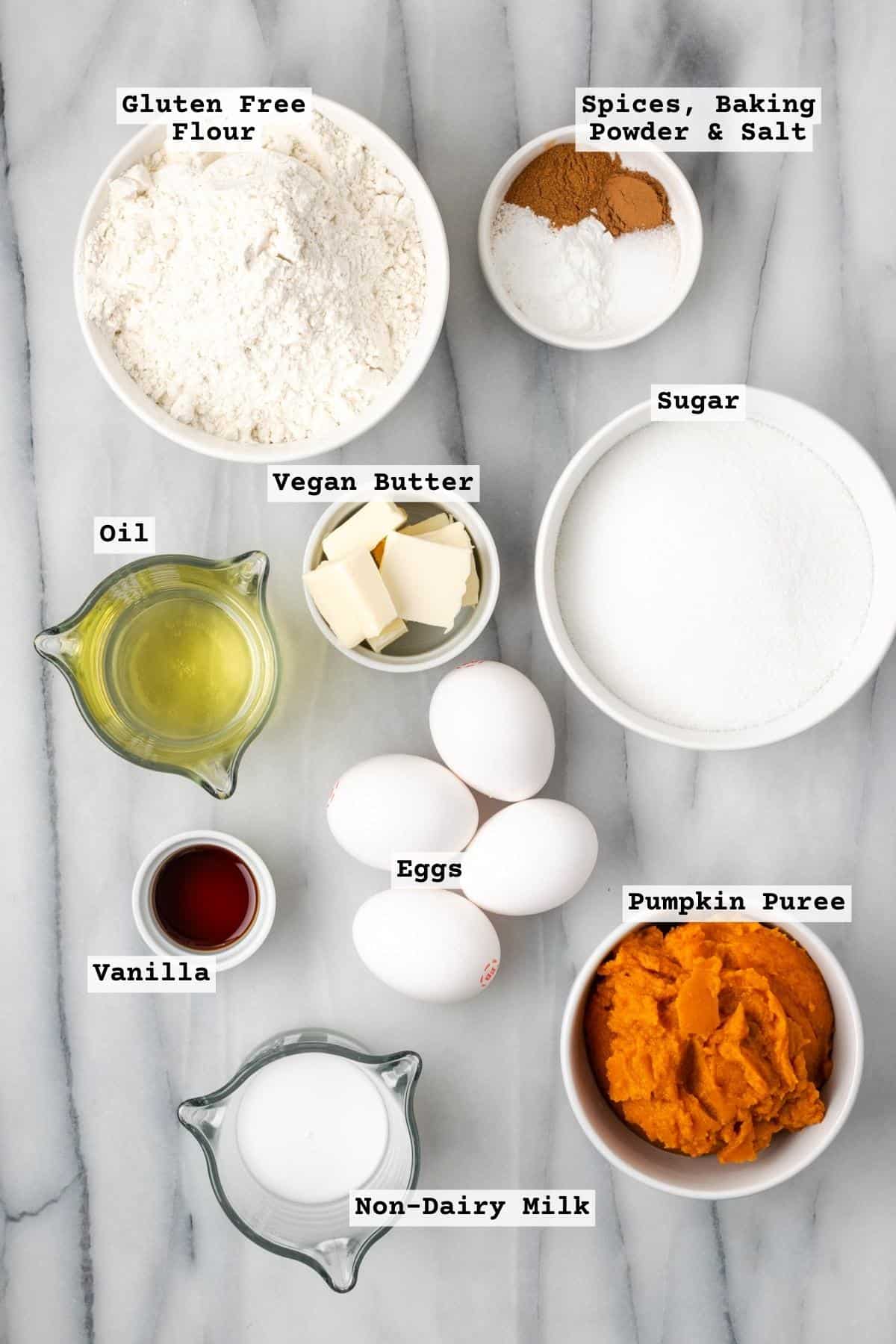 Ingredients for gluten free pumpkin cake on a white marble table.