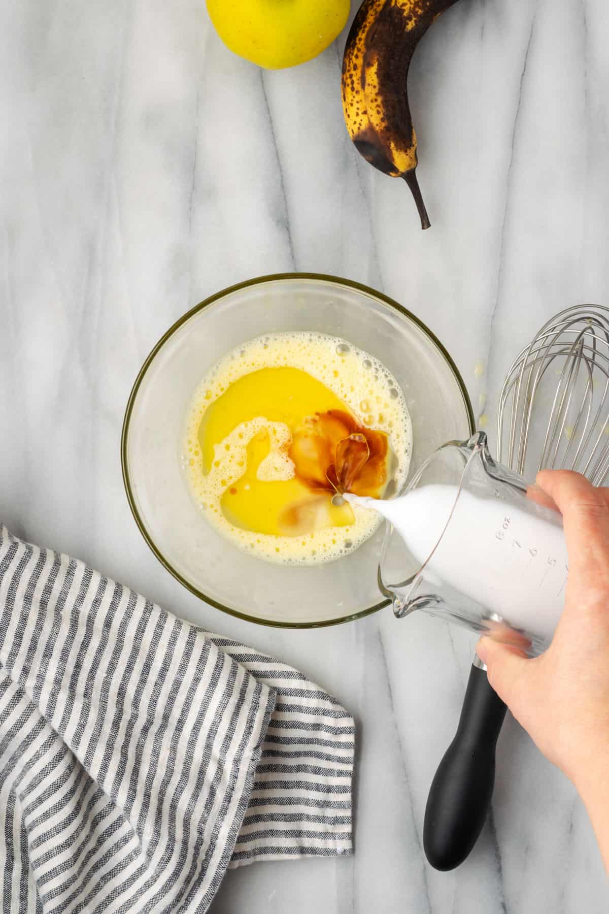 Oil, vanilla and non dairy milk added to a small mixing bowl with a beaten egg.