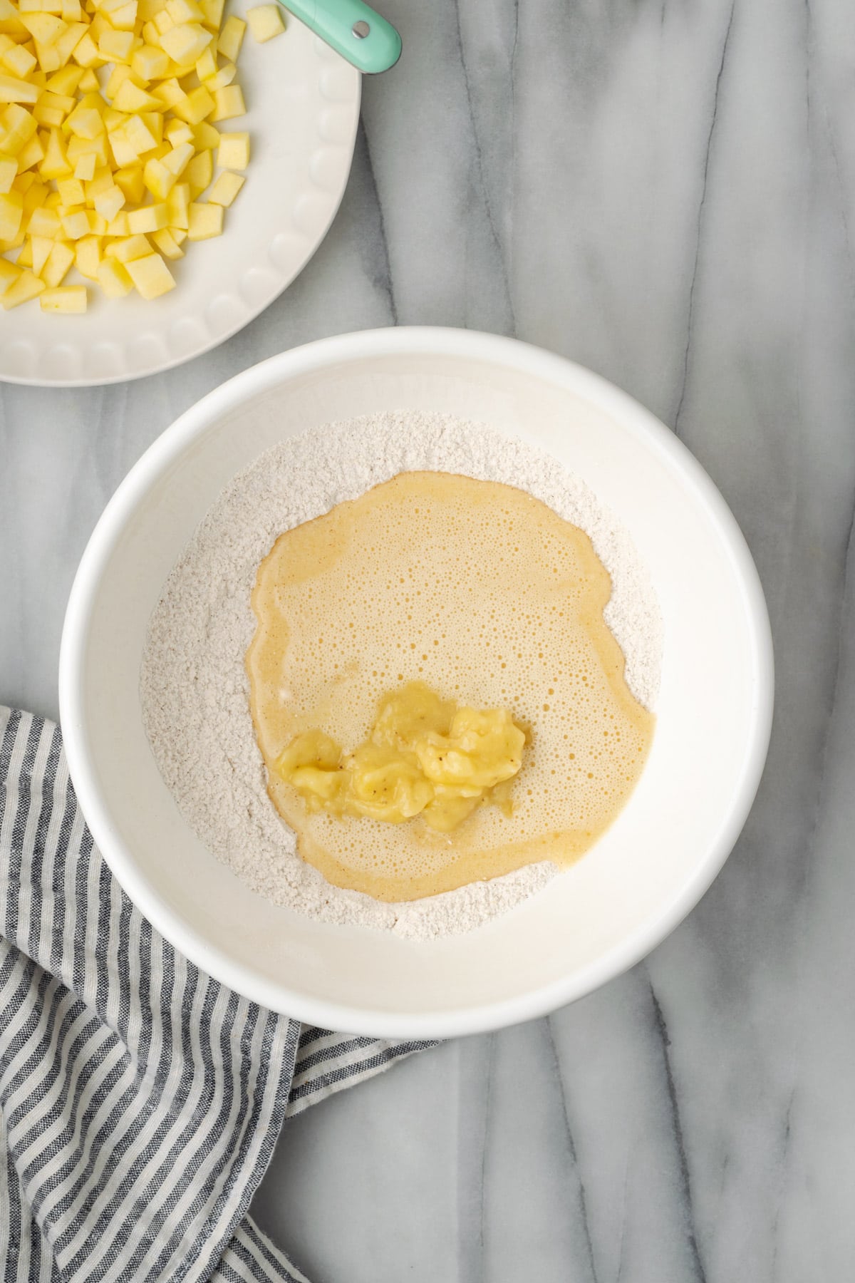 Wet ingredients and mashed banana added to the large mixing bowl with the dry ingredients.