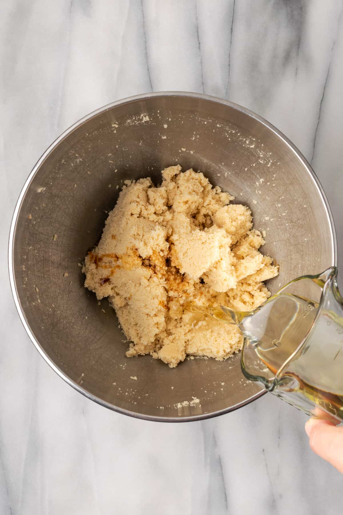 Oil being poured into the mixing bowl with the creamed butter and sugars.