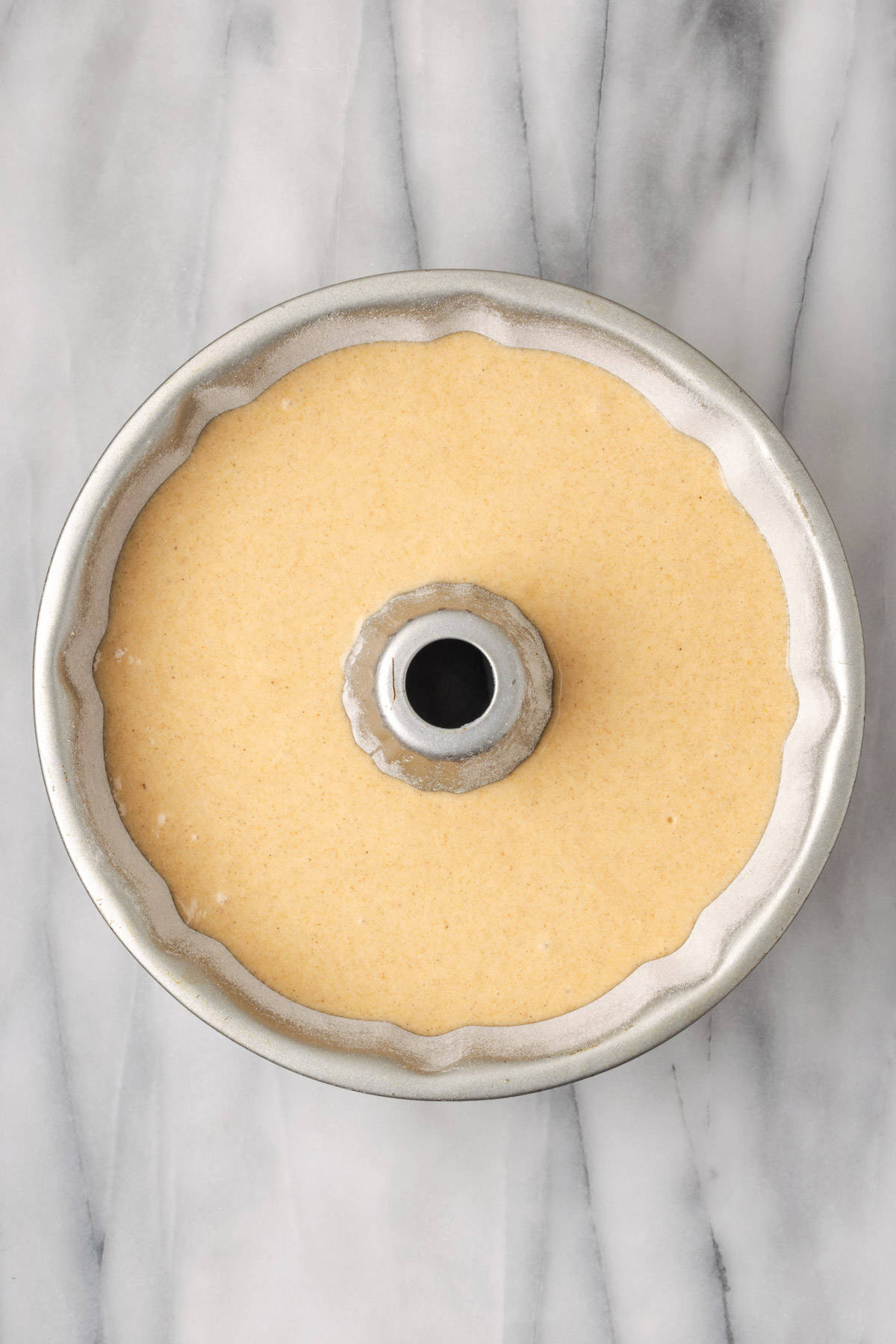 Unbaked apple cider donut cake batter in a round bundt pan.