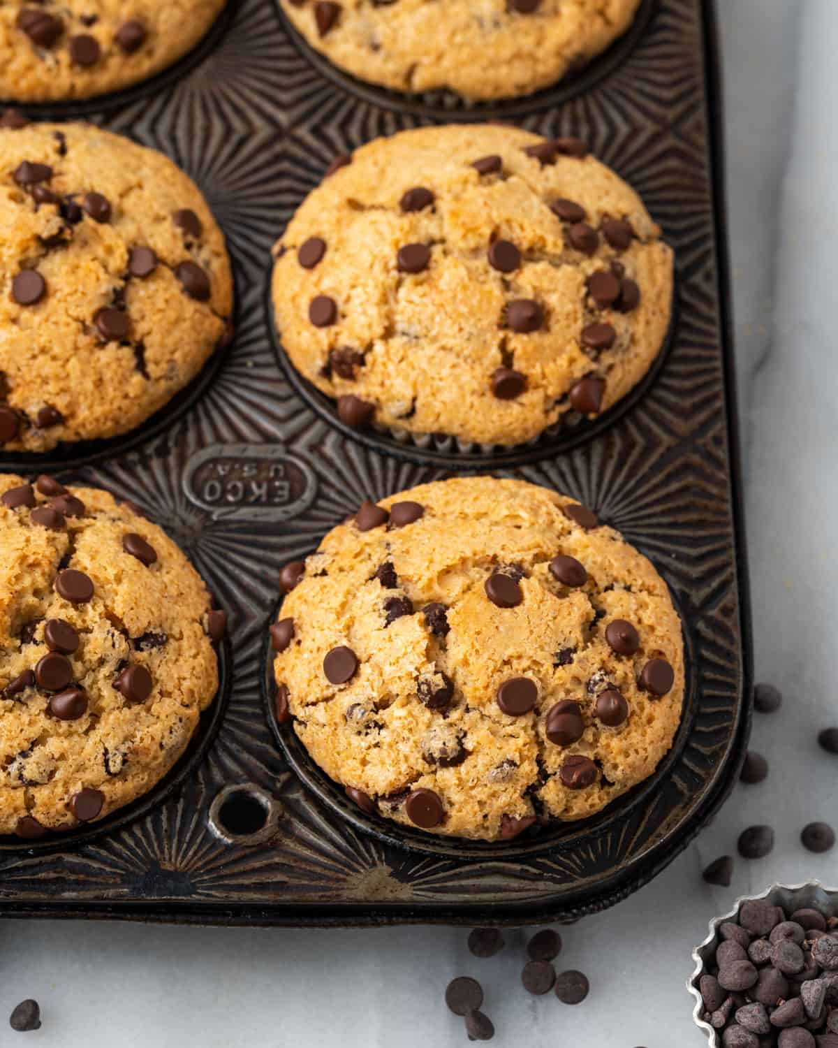 Freshly baked gluten free chocolate chip muffins in a metal baking tin.