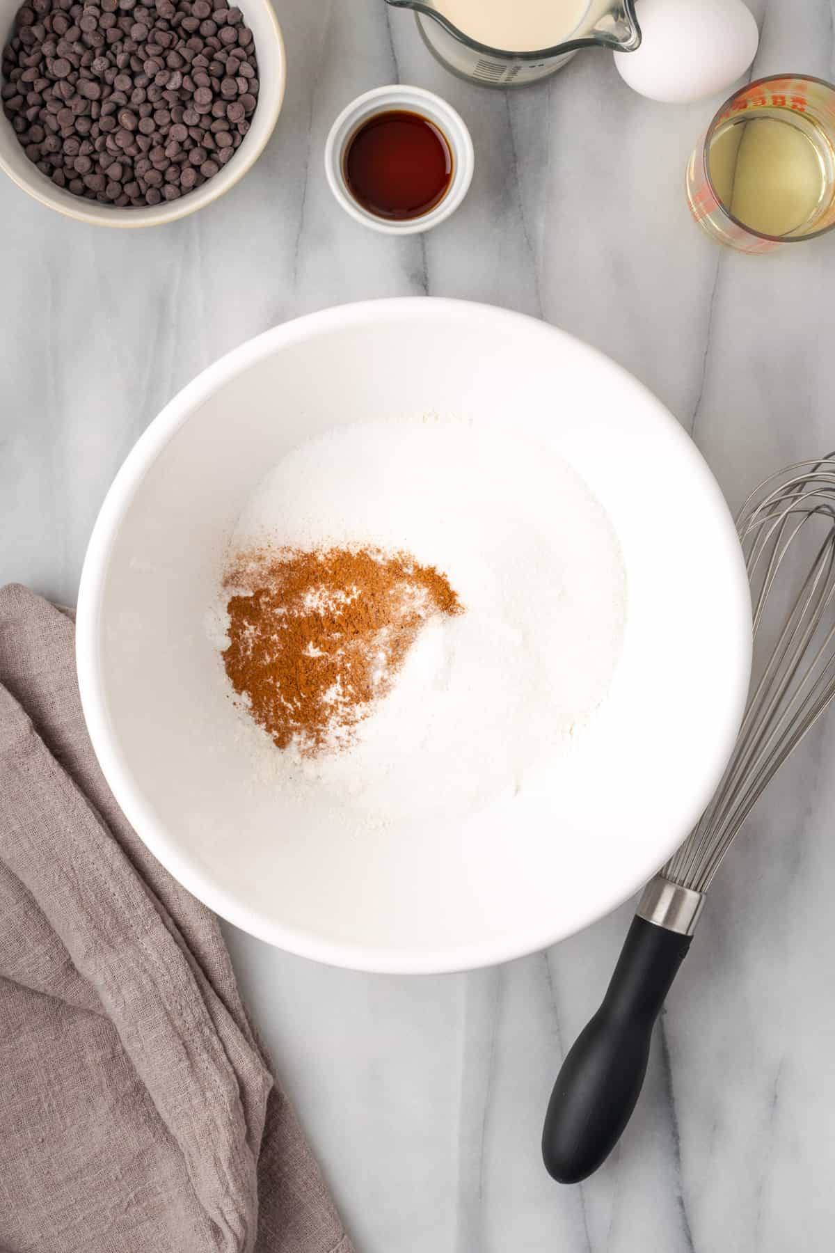 Gluten free flour, sugar, baking powder, salt and cinnamon combined in a large white bowl.