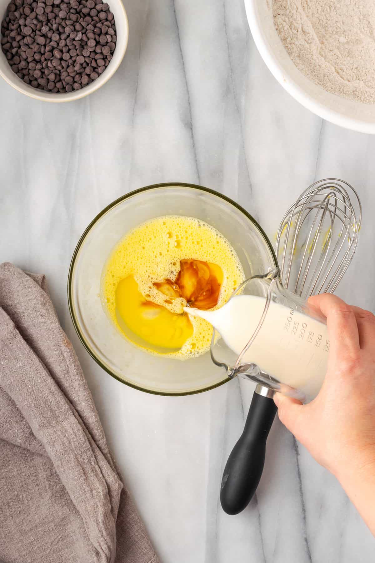 Milk being poured into the bowl with the beaten egg.