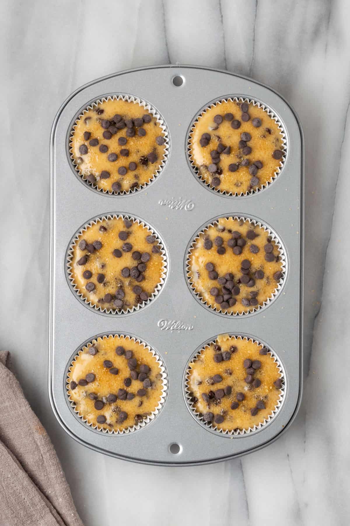 Unbaked gluten free chocolate chip muffin batter in a 6-cup muffin tin.