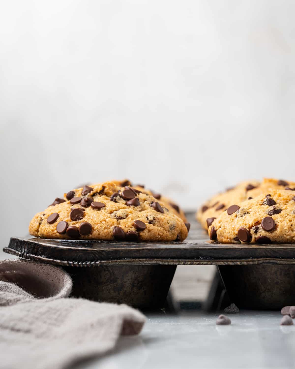 Gluten free chocolate chip muffins in a muffin tin on a marble countertop.