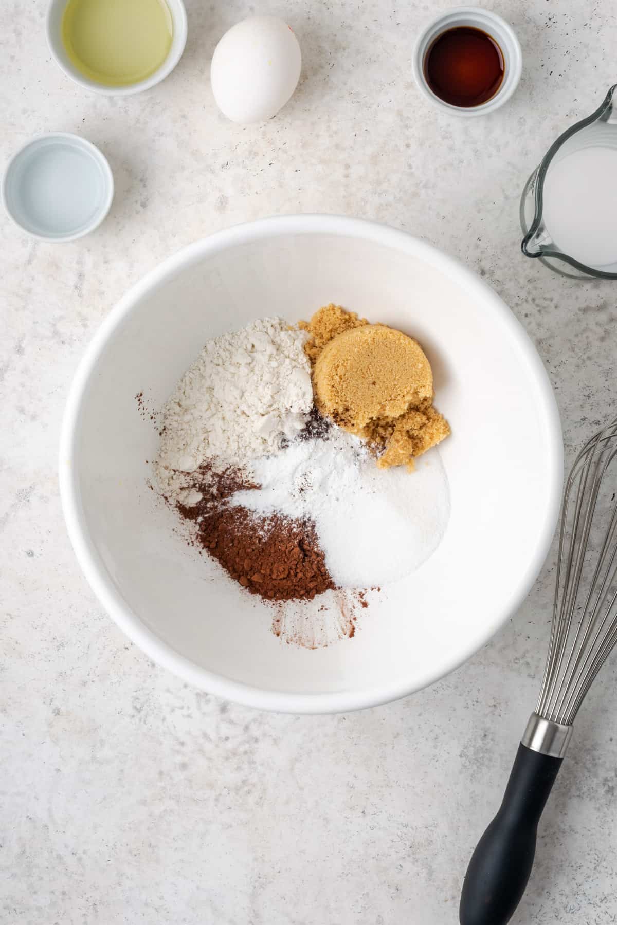 Gluten free flour, cocoa powder, sugar, brown sugar, baking powder, salt and espresso powder combined in a large white mixing bowl.