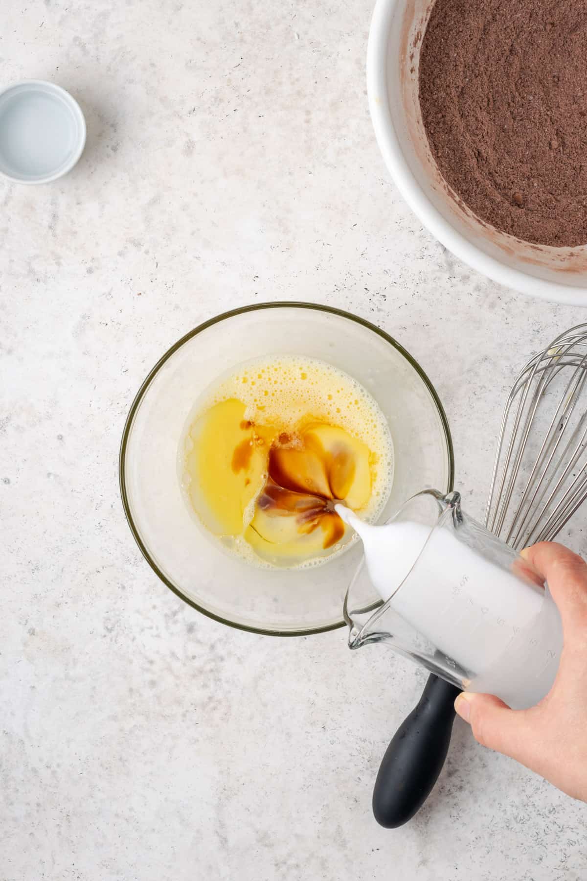 Oil, milk and vanilla being poured into the bowl with the beaten egg.