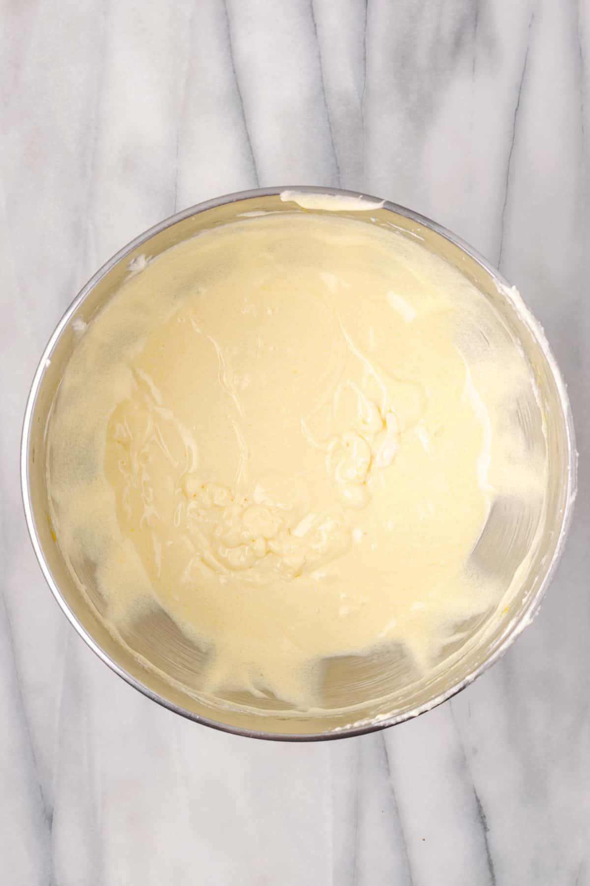 Partially mixed cake batter in a large metal mixing bowl. 