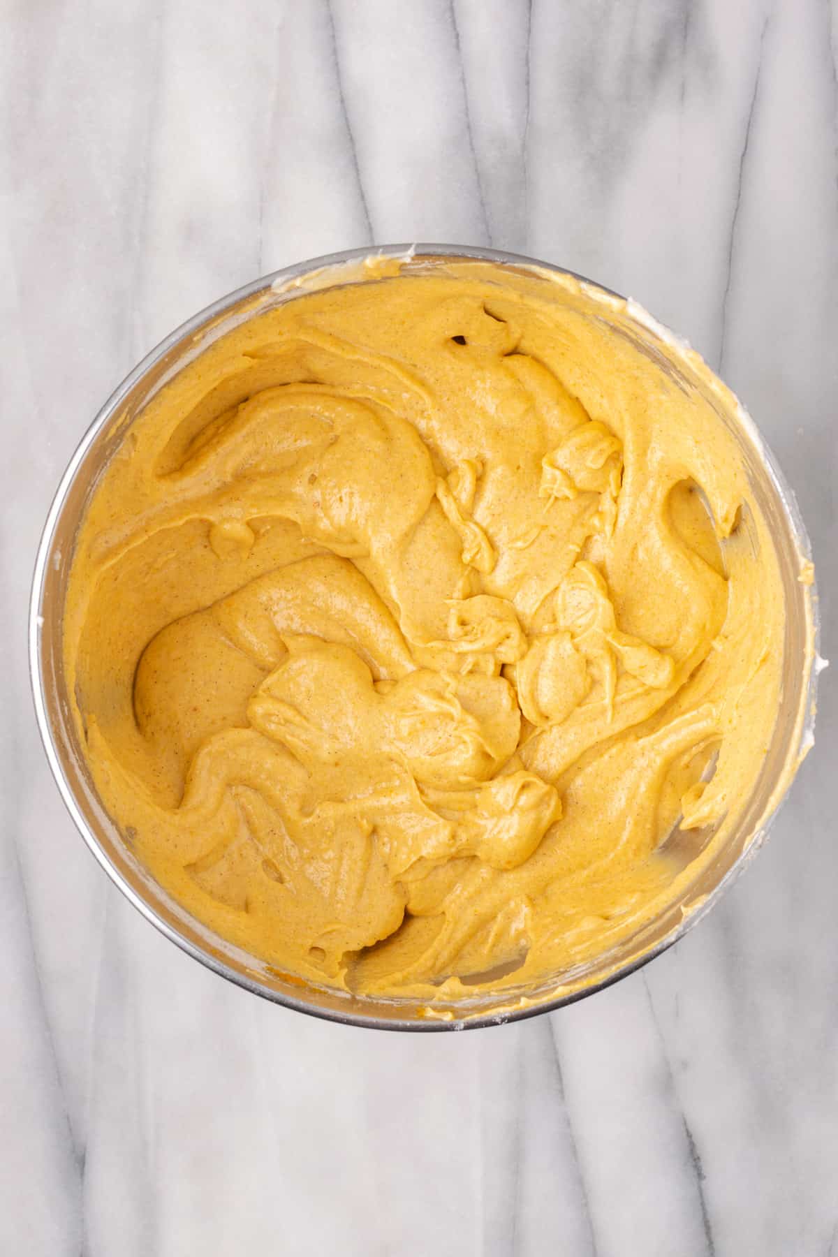 Pumpkin cake batter in a large metal mixing bowl.