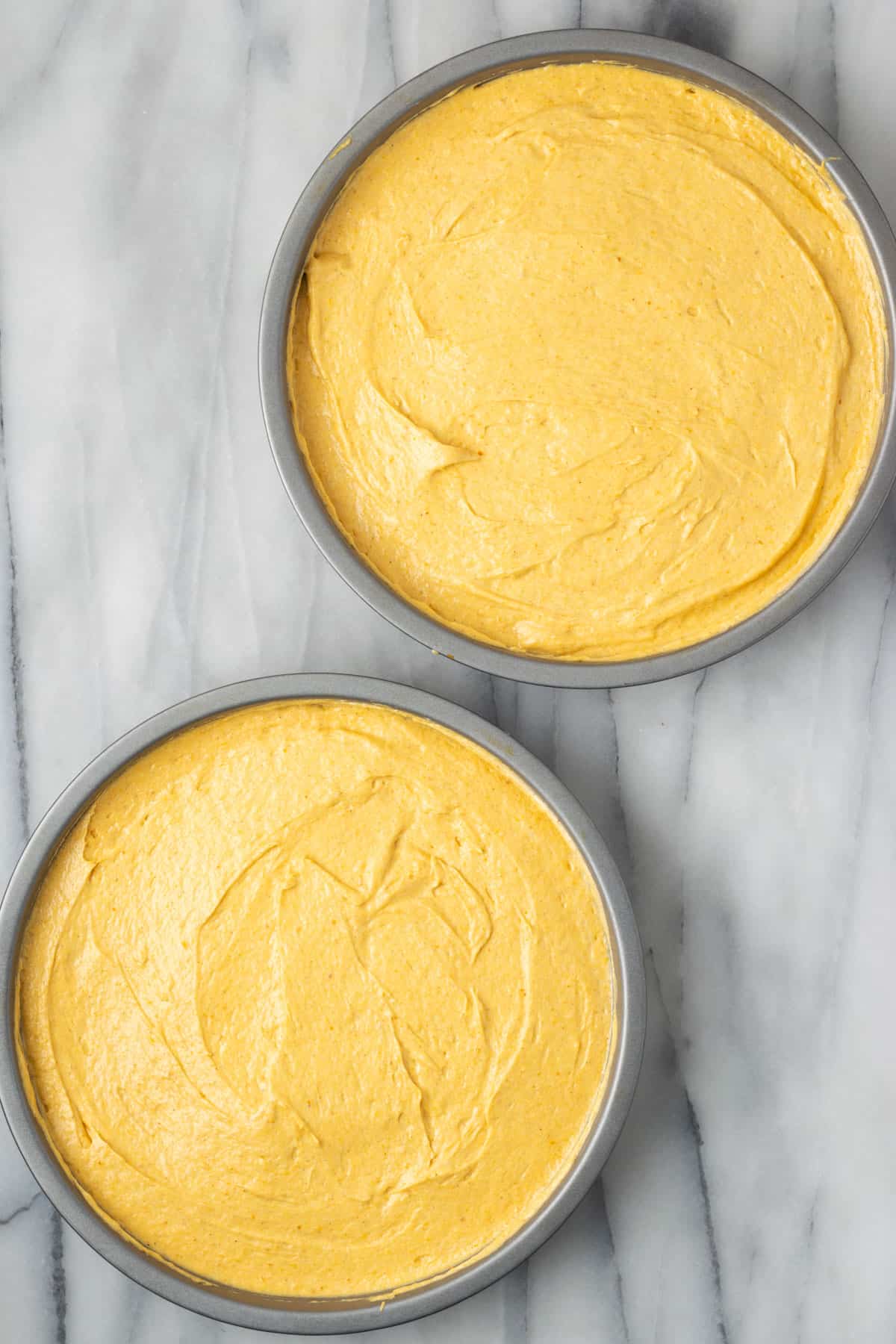 Gluten free pumpkin cake batter spread into two round cake pans.