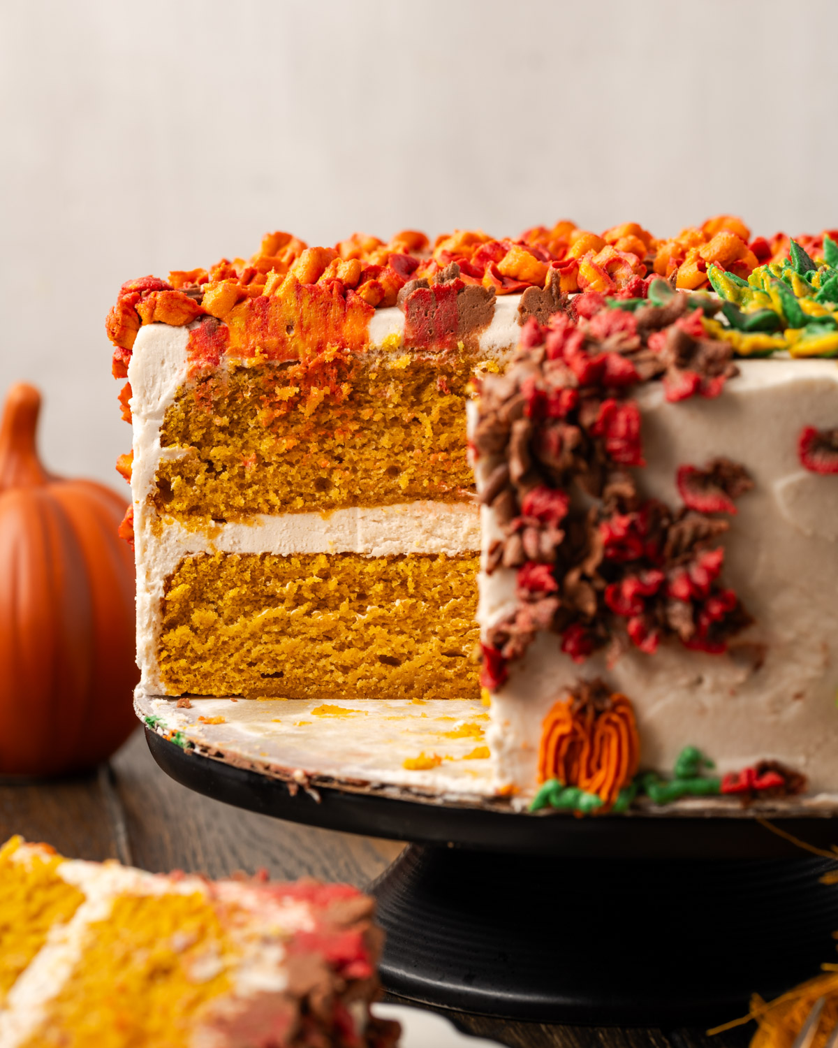 A gluten free pumpkin cake topped with cinnamon buttercream frosting sitting on a black cake stand. 