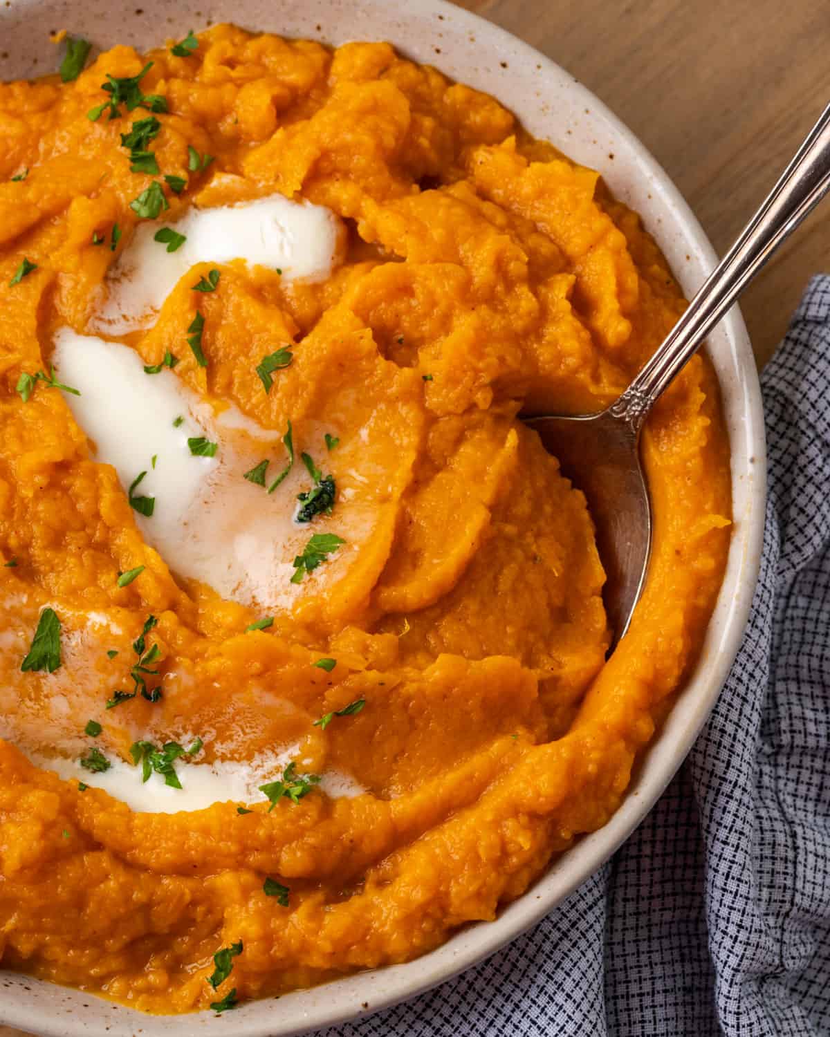 A bowl of mashed sweet potatoes topped with melted butter. 