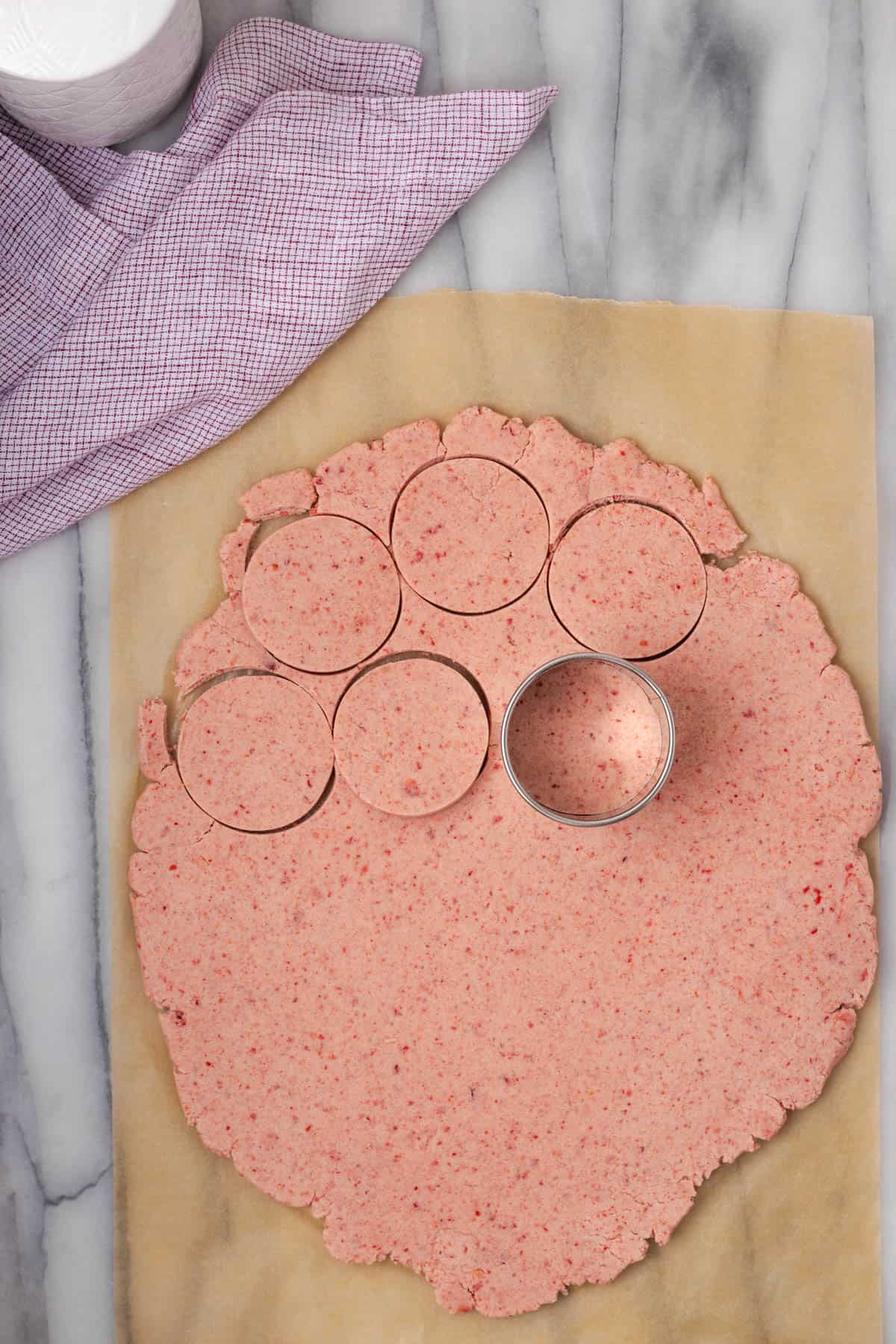 Shortbread dough being cut into circles with a cookie cutter.