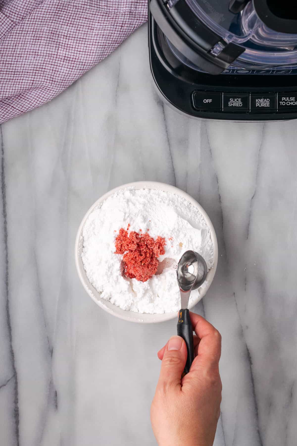 Powdered sugar and pureed freeze dried strawberries in a small white bowl.