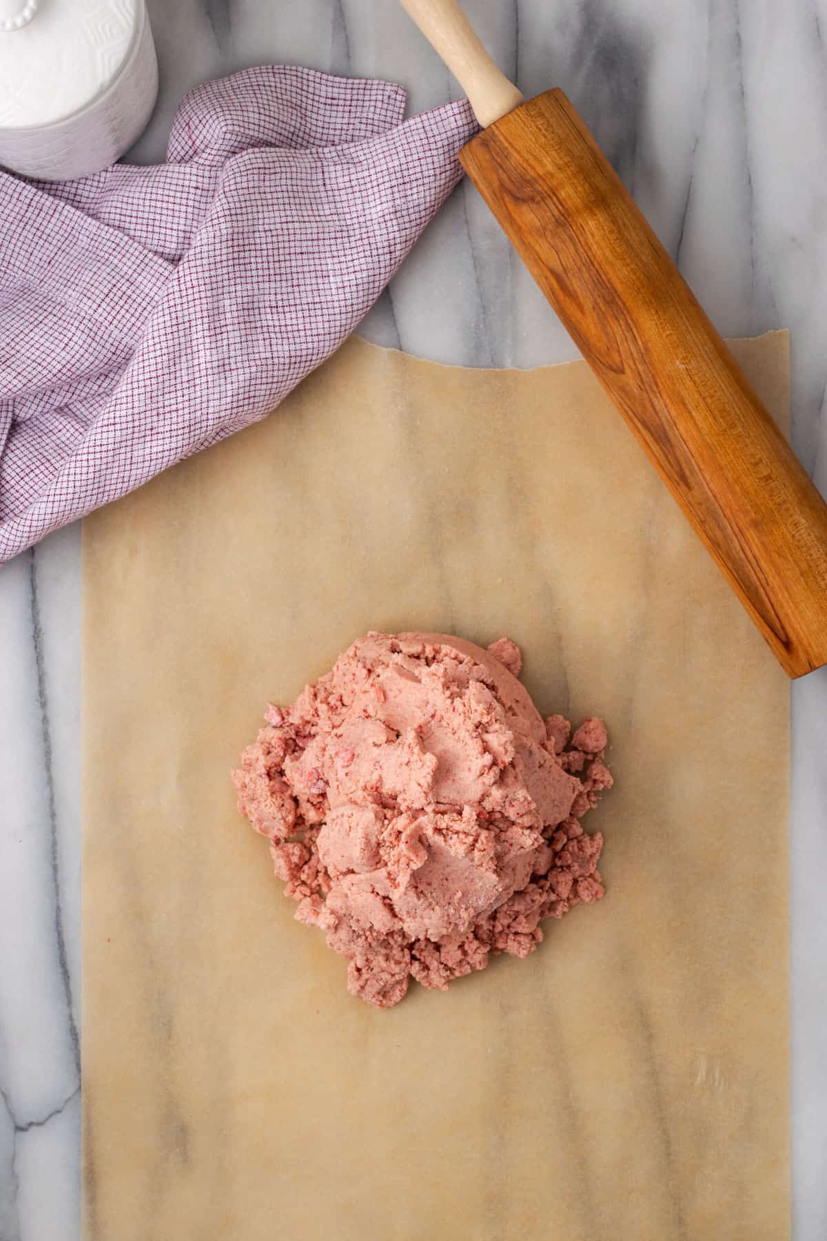 A pile of strawberry shortbread dough sitting on a work table.