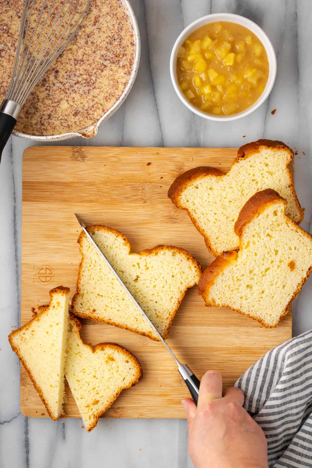 Gluten free bread being sliced in half on a wooden cutting board.