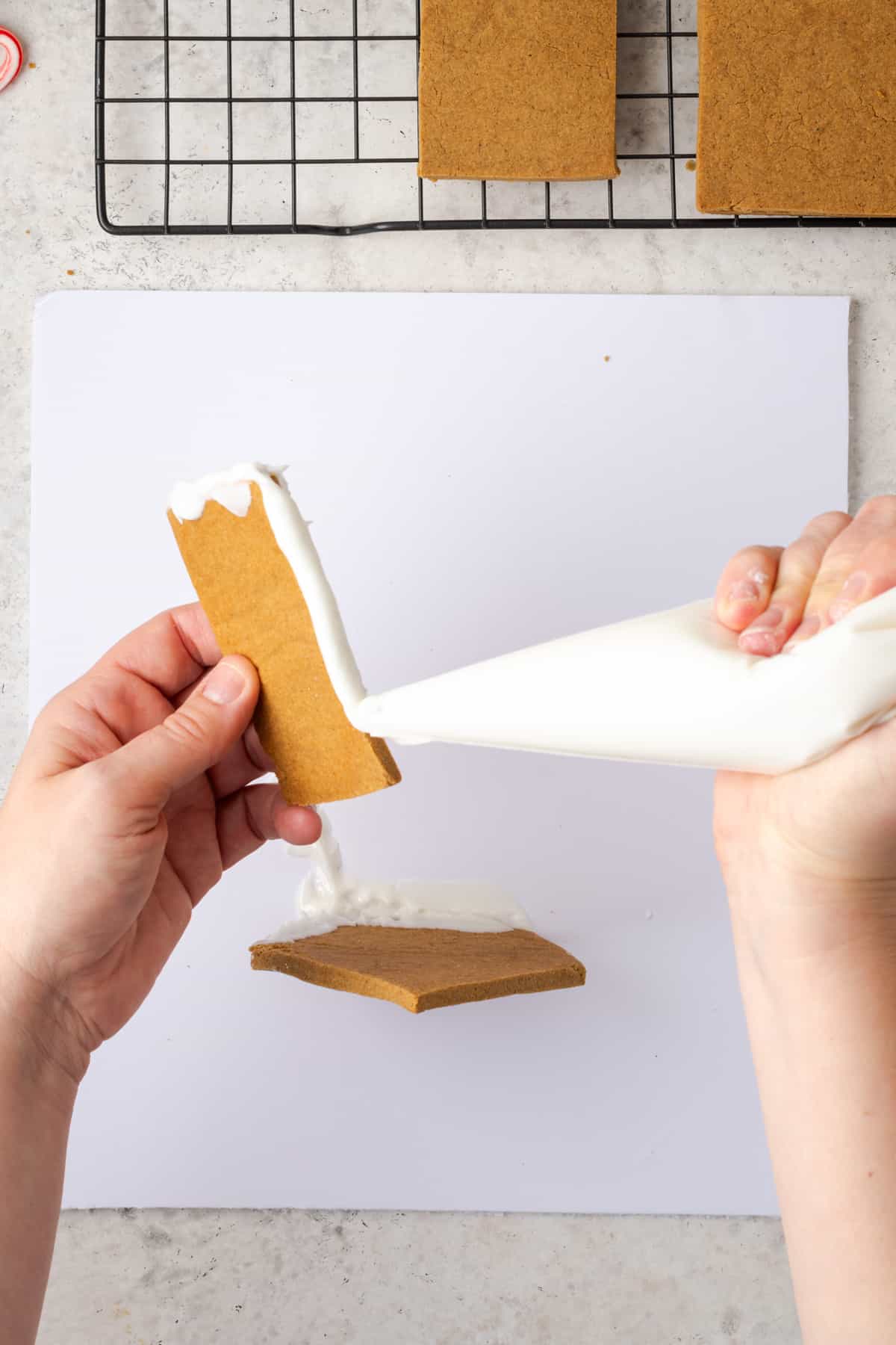 Icing being applied to the bottom long edge and one short edge, forming a L shape. 