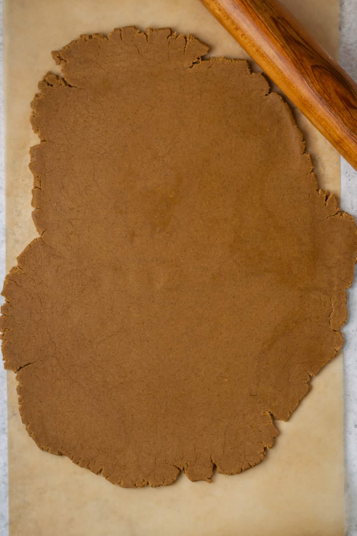 Gluten free gingerbread dough rolled out on a piece of parchment paper.